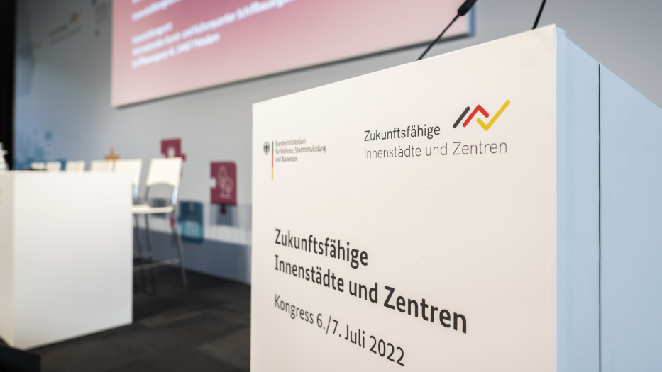 Auf einer leeren Bühne steht ein Rednerpodest mit dem Aufdruck  Auf einer leeren Bühne steht ein Rednerpodest mit dem Aufdruck