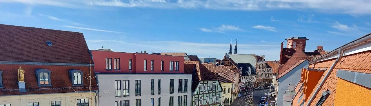 Ein Blick aus erhöhter Perspektive auf eine Straße mit Gebäuden unterschiedlicher Architekturstile, darunter Geschäfte und auffällige Dachfarben. Ein Blick aus erhöhter Perspektive auf eine Straße mit Gebäuden unterschiedlicher Architekturstile, darunter Geschäfte und auffällige Dachfarben.