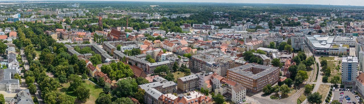 Ein Luftbild einer städtischen Gegend zeigt eine Vielfalt an Gebäuden, baumbestandene Straßen und mehrere Frei- und Grünflächen. Ein Luftbild einer städtischen Gegend zeigt eine Vielfalt an Gebäuden, baumbestandene Straßen und mehrere Frei- und Grünflächen.