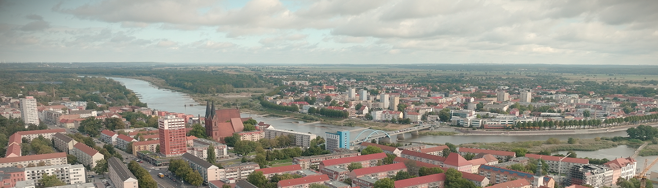 Eine Luftaufnahme einer Stadtlandschaft mit verschiedenen Gebäuden, Straßen und einem Fluss, der sich durch das Gebiet schlängelt. Der Himmel ist bewölkt. Eine Luftaufnahme einer Stadtlandschaft mit verschiedenen Gebäuden, Straßen und einem Fluss, der sich durch das Gebiet schlängelt. Der Himmel ist bewölkt.